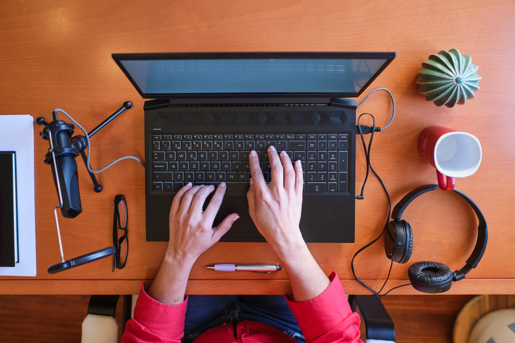 a person's feet on a desk with a laptop and headphones